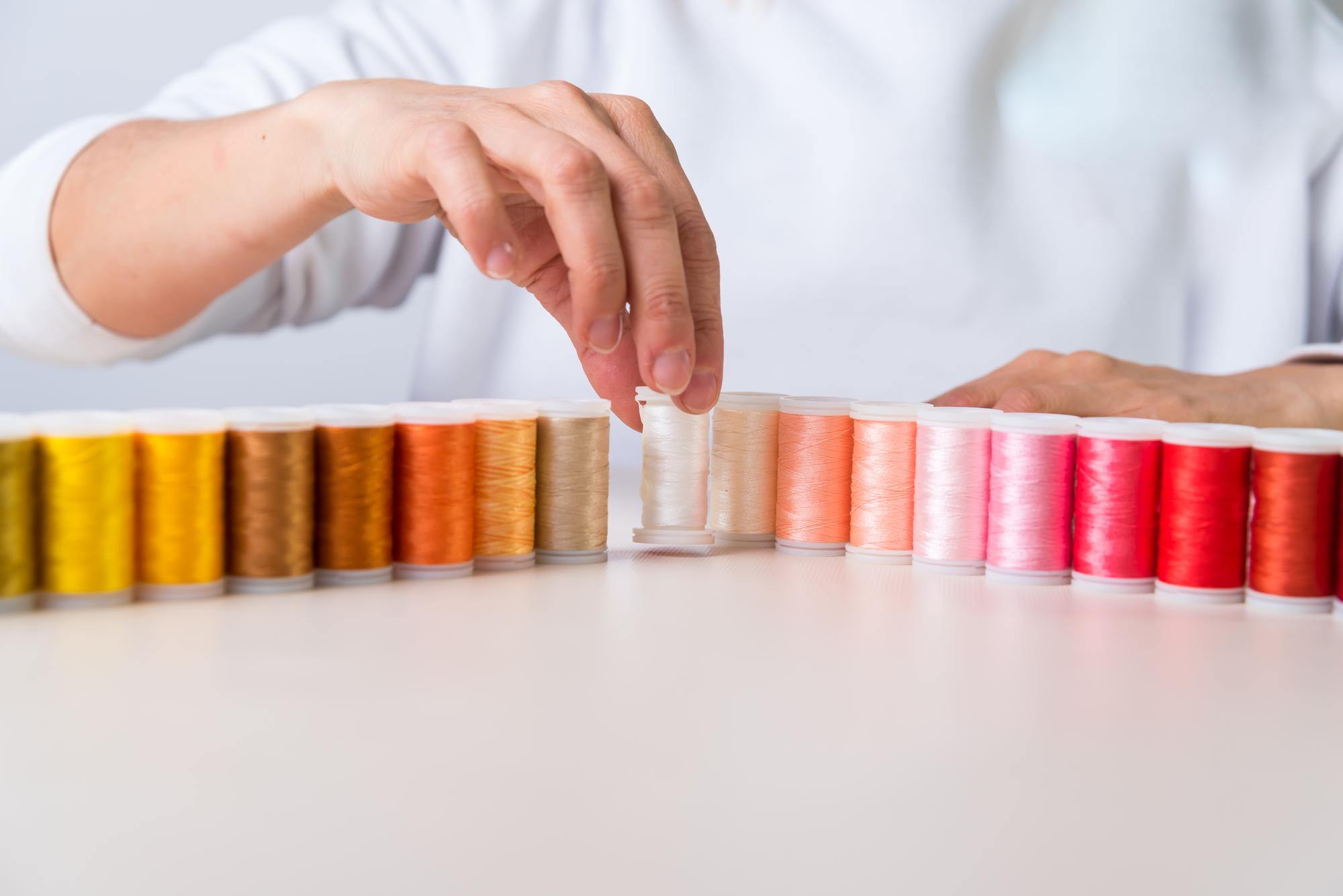 hands checking embroidery samples on a table